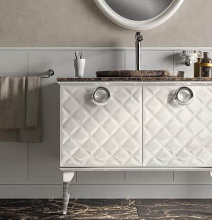 White bathroom vanity with diamond-patterned doors, marble countertop and round mirror above.
