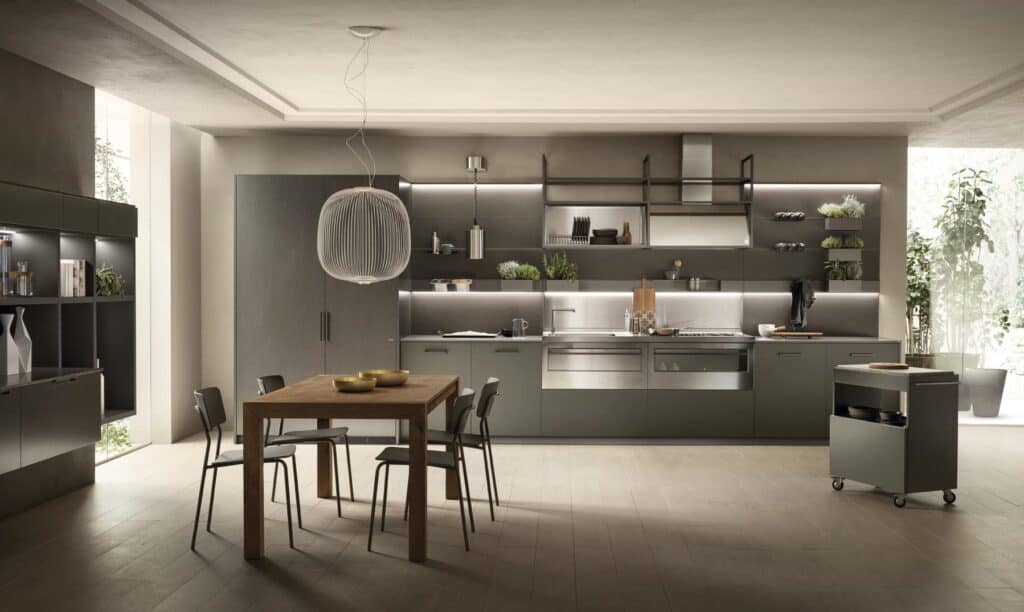 Modern kitchen interior with grey cabinetry, stainless steel appliances, a wooden dining table with four chairs, and a pendant light above.