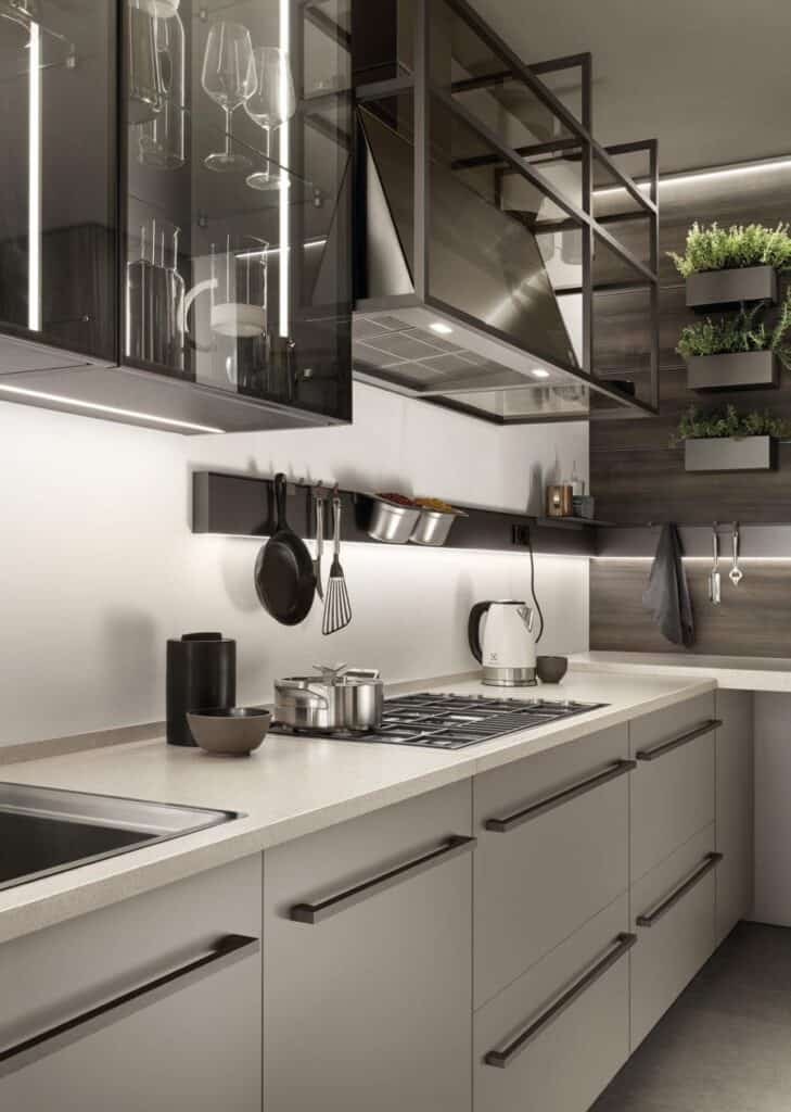 Modern kitchen with sleek cabinetry, a cooktop, kettle, utensils on a rail, and organized shelving.