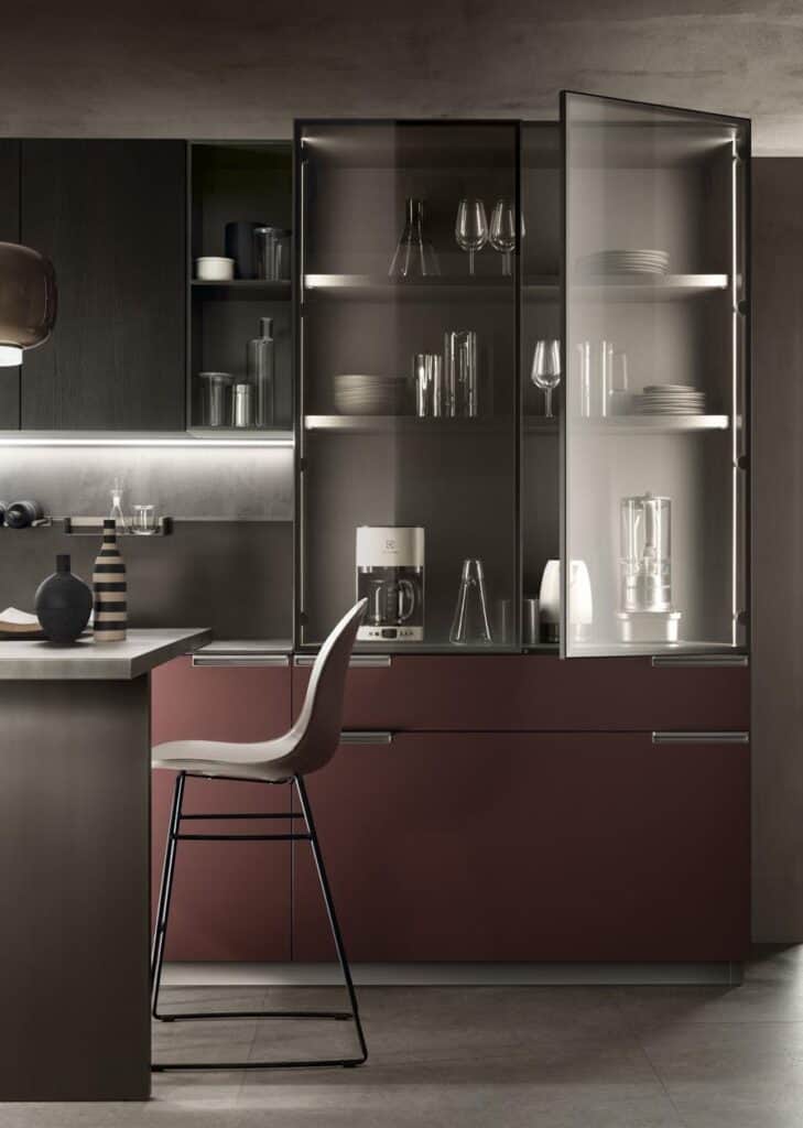 Modern kitchen interior with dark cabinetry, glass-fronted cabinets, a kitchen counter, and a high chair.