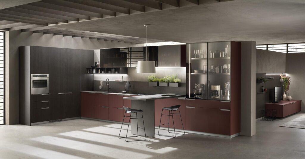 Modern kitchen with dark cabinetry, integrated appliances, a central island with stools, and decorative plants under a sleek, architectural ceiling.