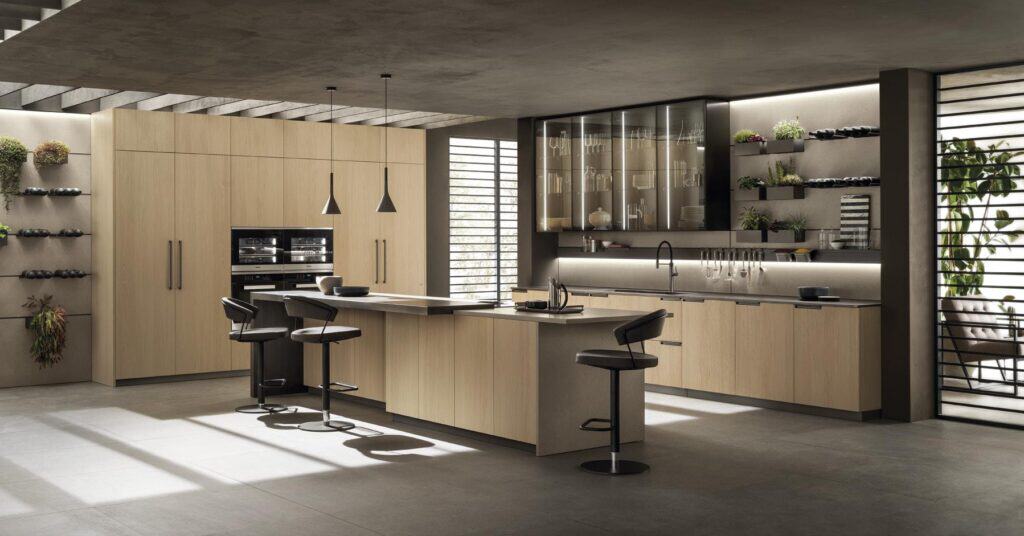 Modern kitchen with wooden cabinets, an island with bar stools, pendant lights, and open shelves displaying plants and dishes.