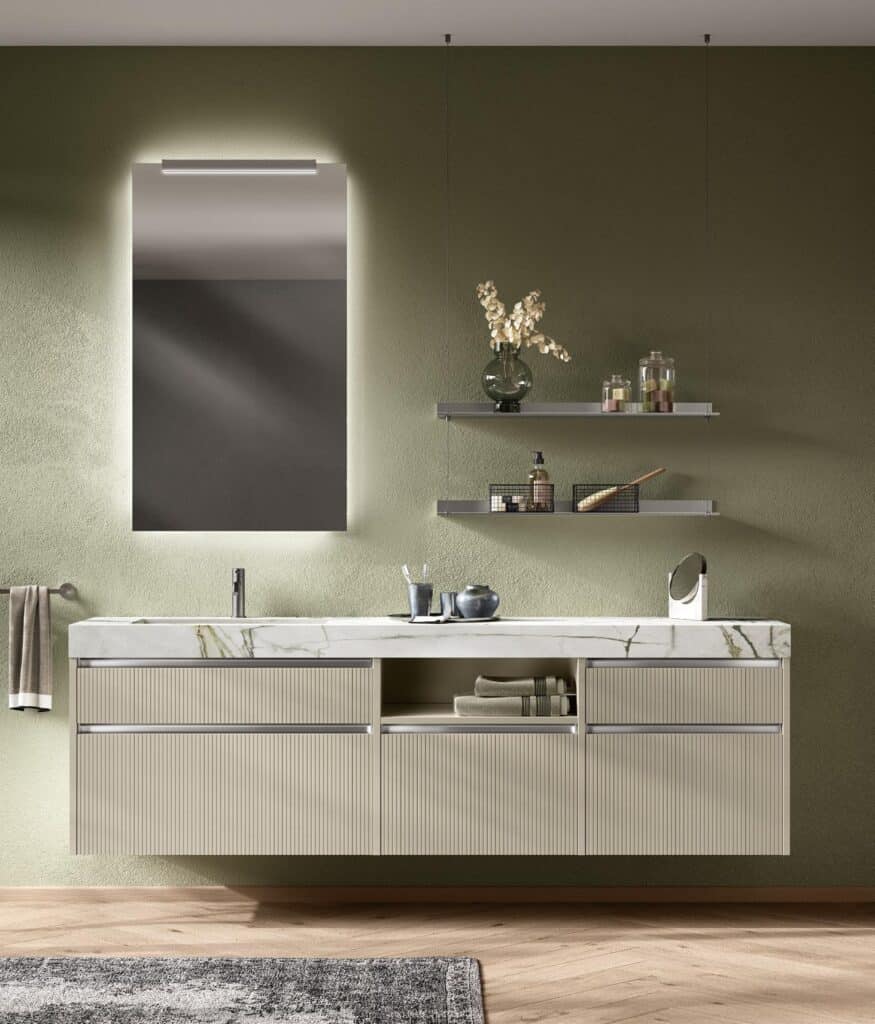 Modern bathroom with a wall-mounted vanity, marble countertop, illuminated mirror, and two floating shelves on a green wall.