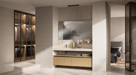 Modern bathroom with a large mirror, wooden vanity, and integrated shelving, adjacent to a walk-in closet and a bedroom.