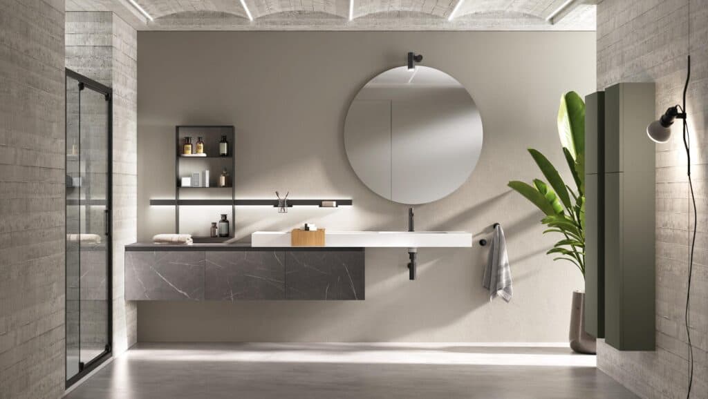 Modern bathroom with a round mirror, floating vanity, open shelving, a potted plant, and a glass shower door.