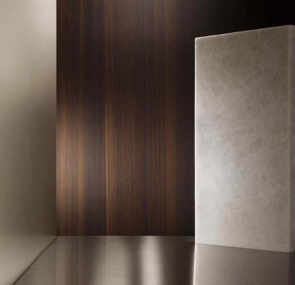 Minimalist interior with a dark wooden wall and a smooth beige marble surface.