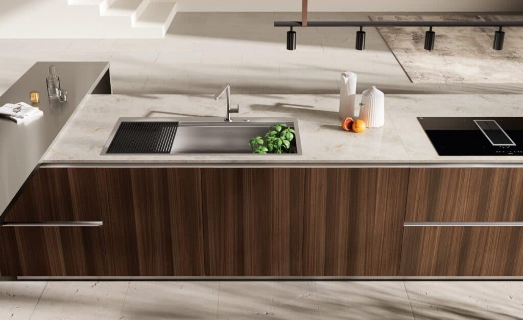 Modern kitchen countertop with a sink, faucet, potted plant, fruit, and kitchen appliances.