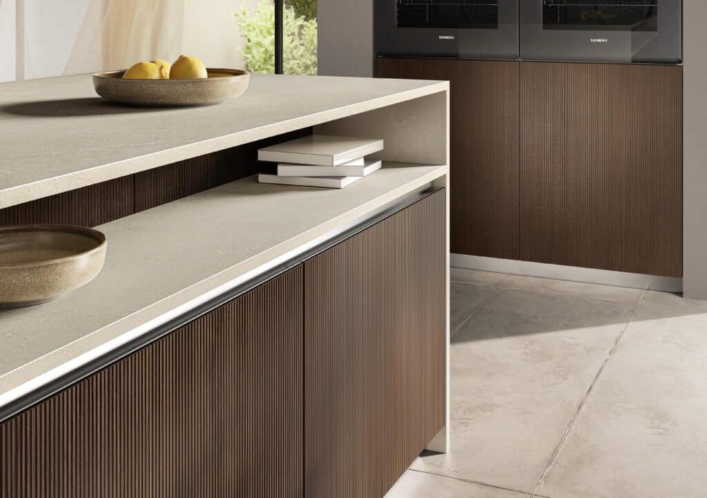 Modern kitchen with brown cabinetry, light stone countertops, a bowl of lemons, and stacked books.