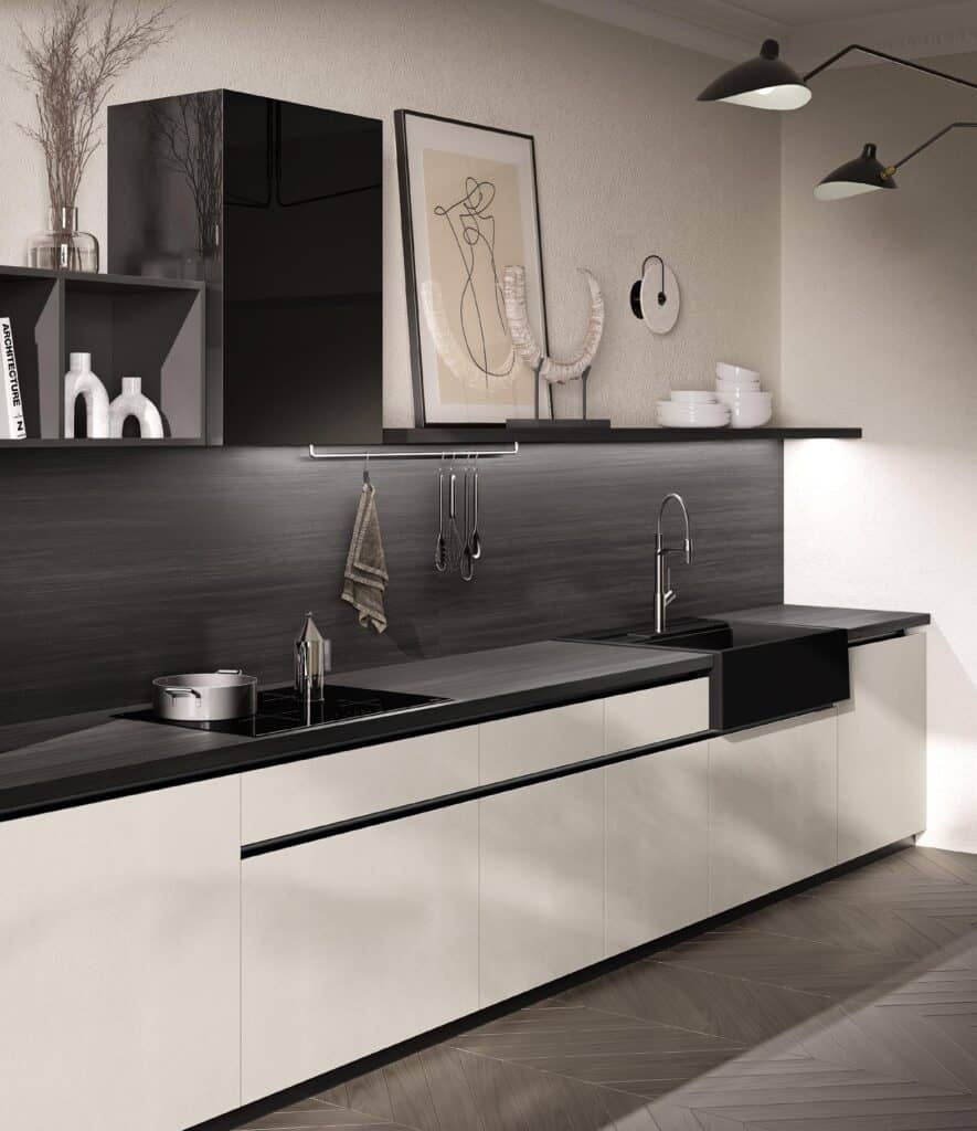 Modern kitchen interior with white cabinets, black countertop, wall-mounted shelves, abstract artwork, and ceiling lights.