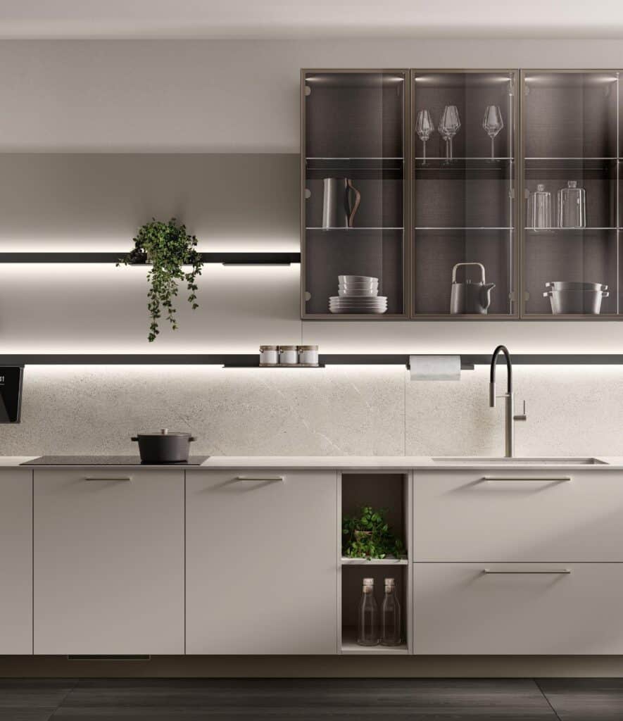 Modern kitchen interior with light gray cabinetry, glass wall cabinets displaying glassware, under-cabinet lighting, countertop with a pot, and a sleek faucet.