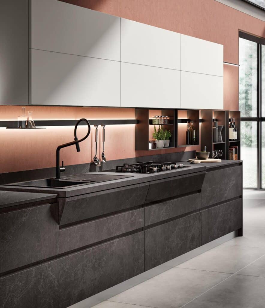 Modern kitchen interior with sleek dark cabinetry, integrated stovetop, sink with a black faucet, overhead cabinets, under-cabinet lighting, and open shelves displaying plants and kitchen items.
