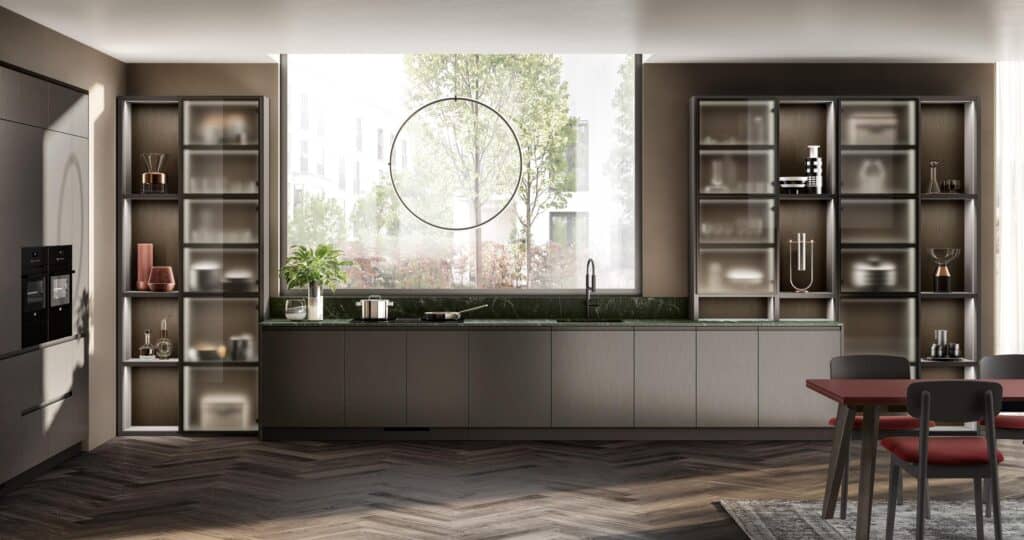 &quot;Modern kitchen with sleek grey cabinets, large window with a circular accent, green marble countertop, open shelving, and a dining area with red and black chairs.&quot;