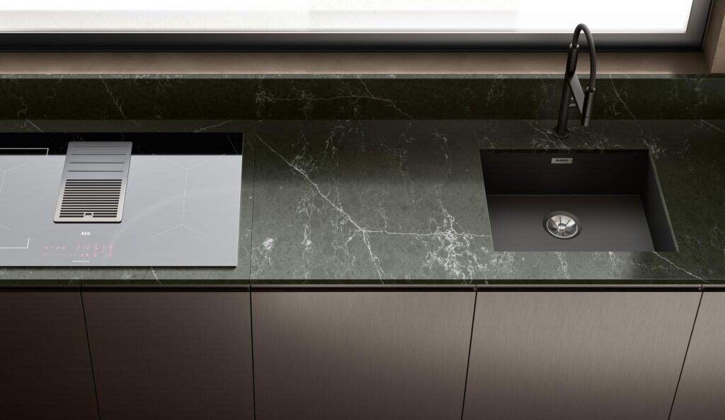 Modern kitchen countertop with a built-in stovetop and sink, featuring dark marble finish and stainless steel accents.