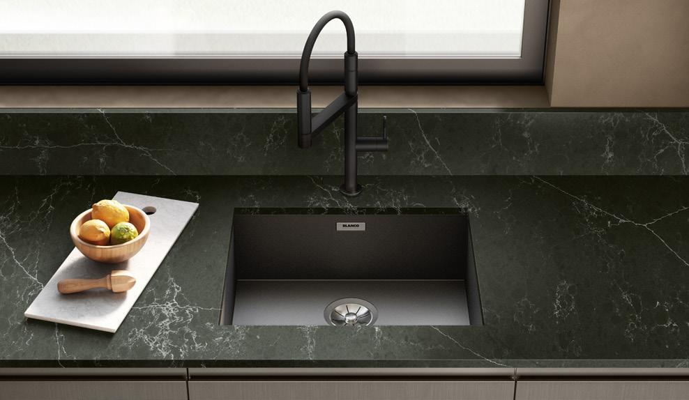 Dark green marble kitchen countertop with an integrated black sink and modern faucet. A cutting board with a lemon, lime, and wooden juicer rests beside the sink.