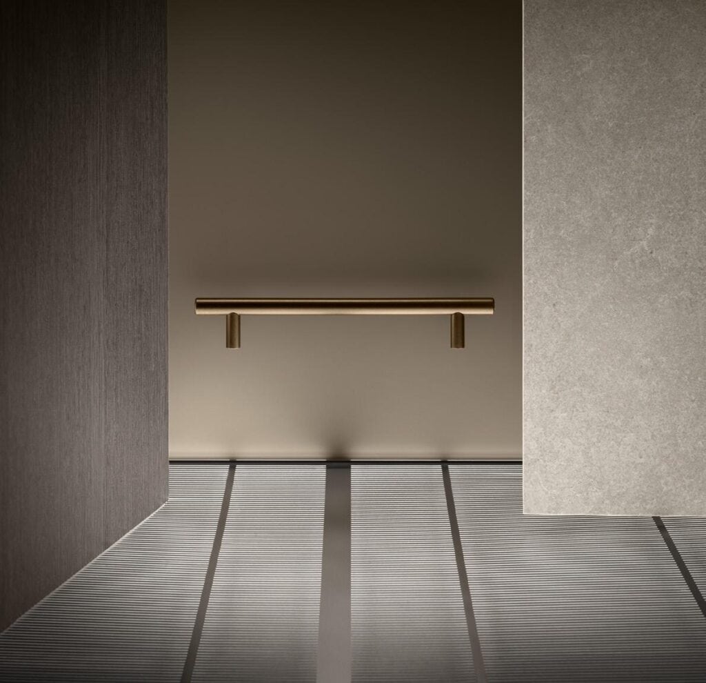 Minimalistic interior with a beige wall, horizontal brass handle, and vertical textured panels.