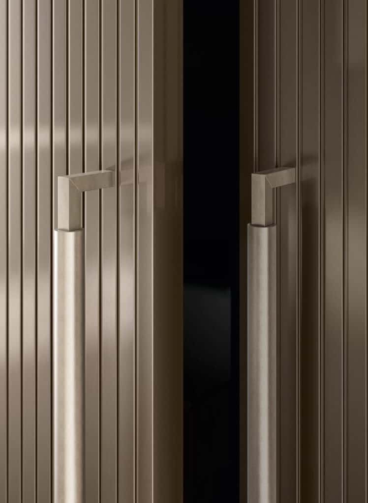 Close-up of partially open double doors with vertical grooves and square metal handles.