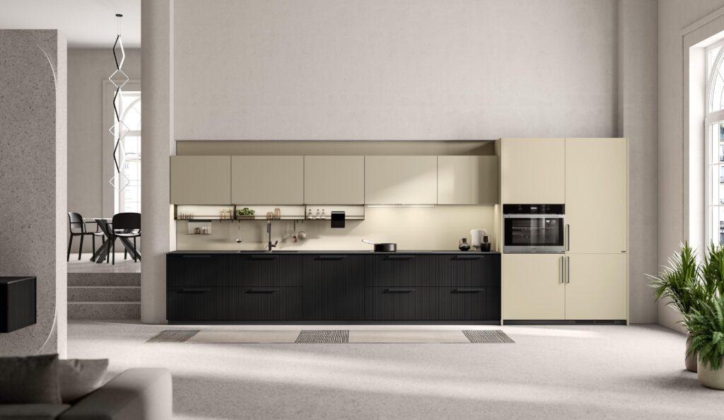 Modern kitchen interior with beige cabinetry, black lower cabinets, and built-in appliances, adjacent to a dining area with a table and chairs in the background.