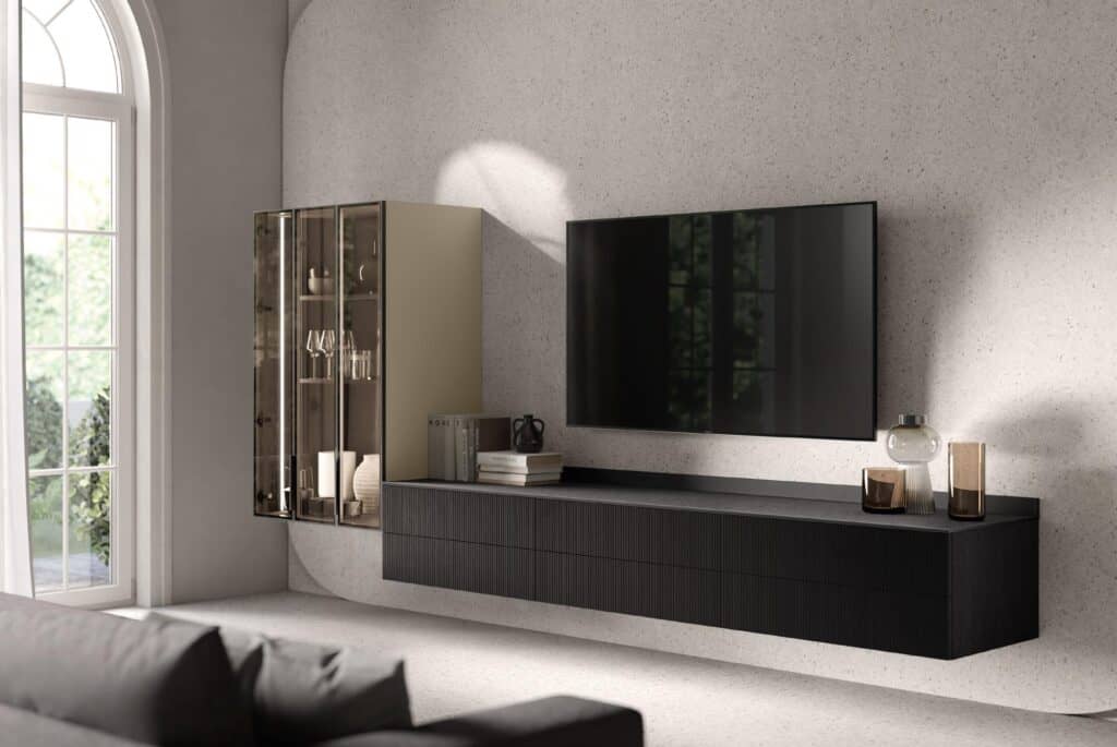 Modern living room with a large wall-mounted TV and a sleek floating shelf beneath it. A glass cabinet displaying items is on the left, and there is a large arched window on the side.