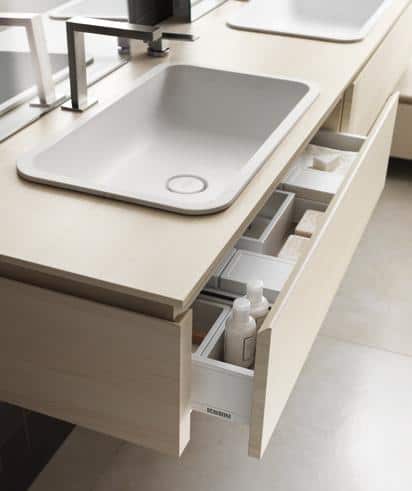 Modern bathroom sink with open drawer storage underneath, containing toiletries and organizers.