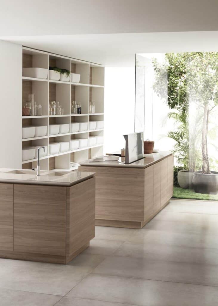Modern kitchen with light wood cabinets, open shelving with white containers, and a large window showcasing greenery outside.