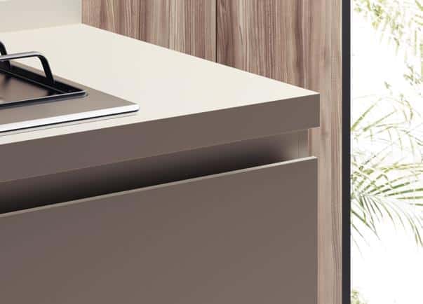 Modern kitchen counter with beige surface, a built-in stovetop, and wood panel background.