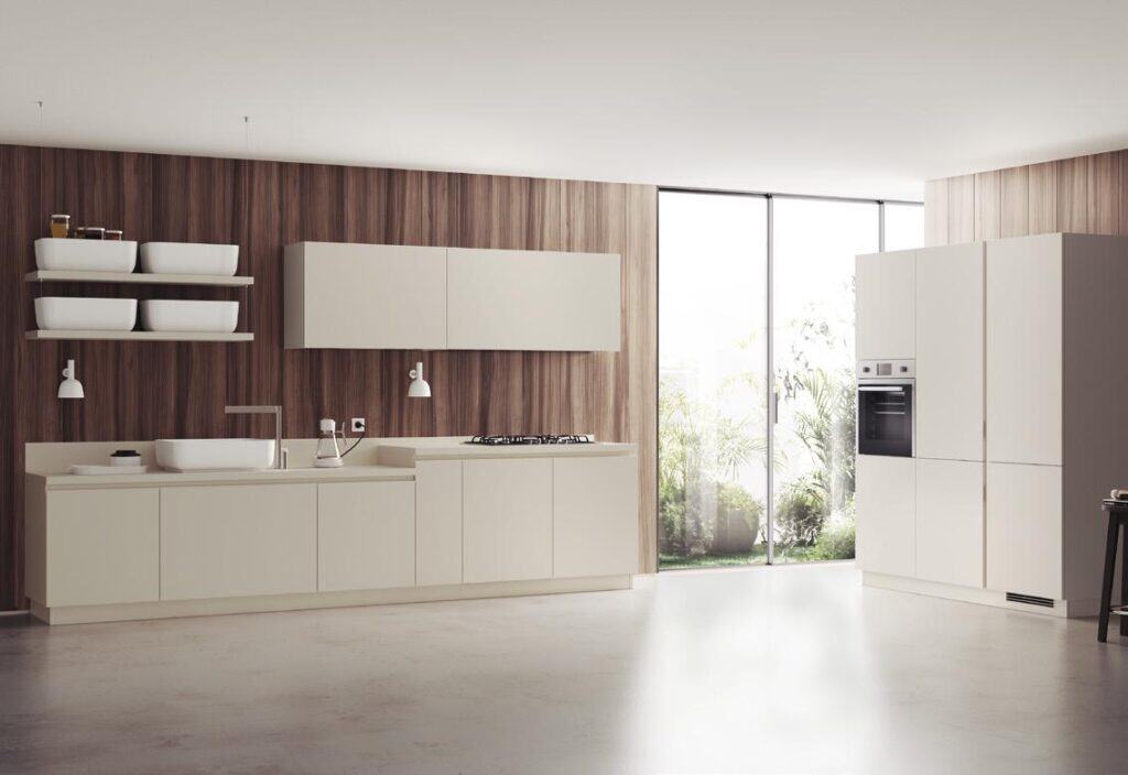 Modern kitchen with light cabinets, a wooden accent wall, built-in appliances, and large windows overlooking greenery.