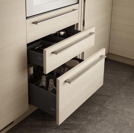 Open wooden kitchen drawers containing utensils and bottles.
