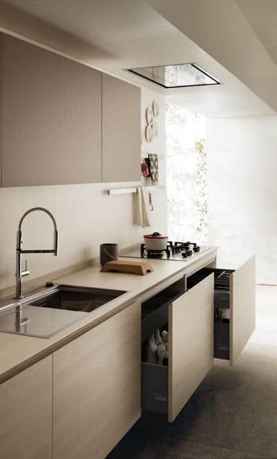 Modern kitchen with beige cabinets, pull-out drawers, a stainless steel sink, and a minimalist stove.