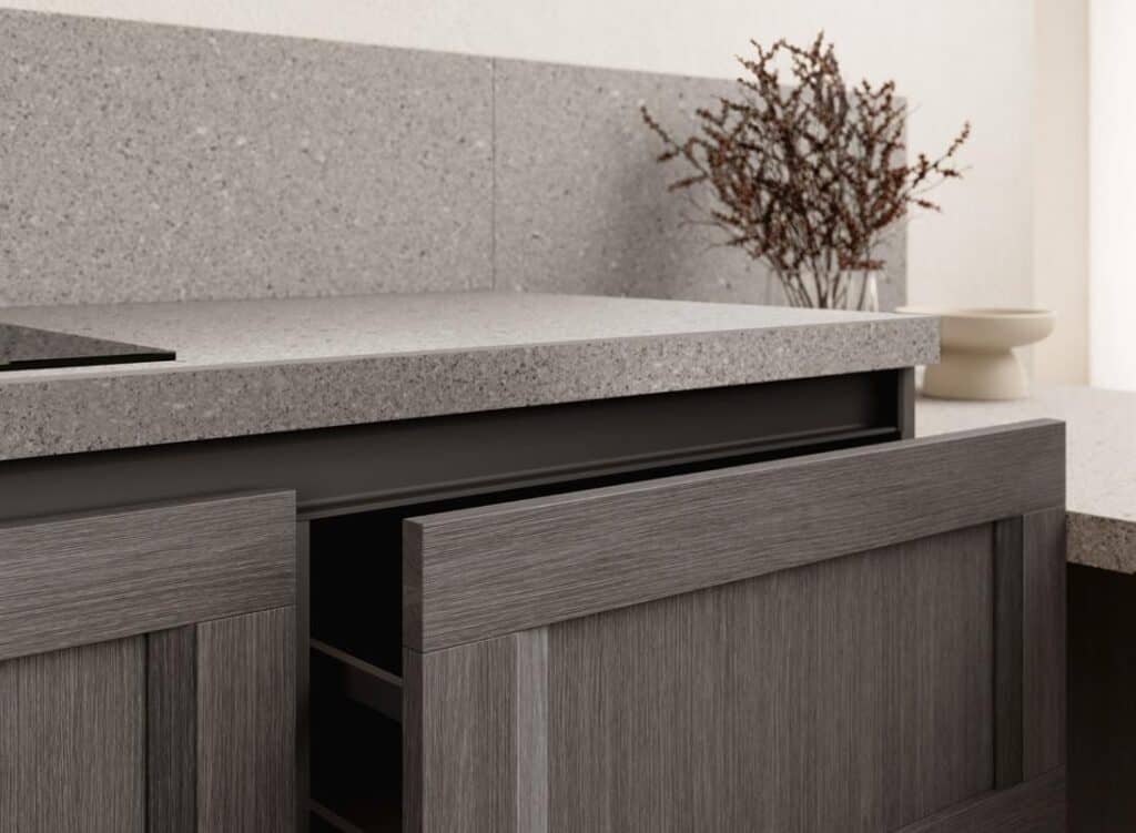 Modern kitchen with sleek gray cabinets, a textured countertop, and dried branches in a white vase.