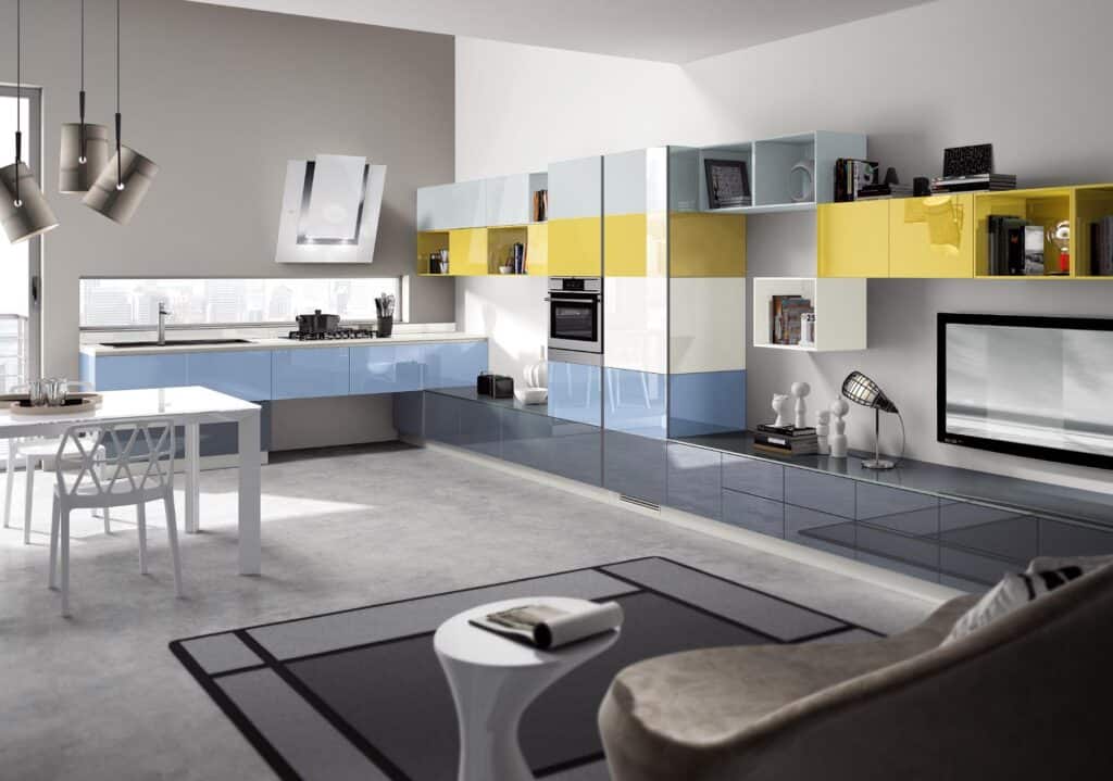 Modern kitchen and living area with colorful cabinets in blue and yellow, a dining table with white chairs, and a sleek TV unit.