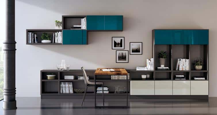 Modern home office setup with a wooden desk, dark framing, teal cabinets, assorted books, and decorative plants against a beige wall.