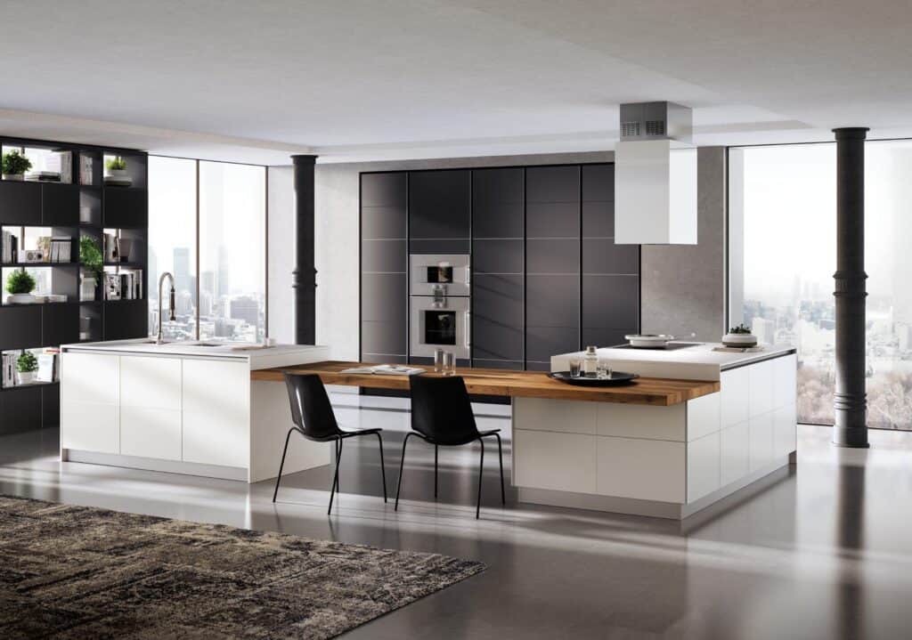 Modern kitchen interior with white cabinets, wooden countertops, black chairs, and a large window overlooking a cityscape.