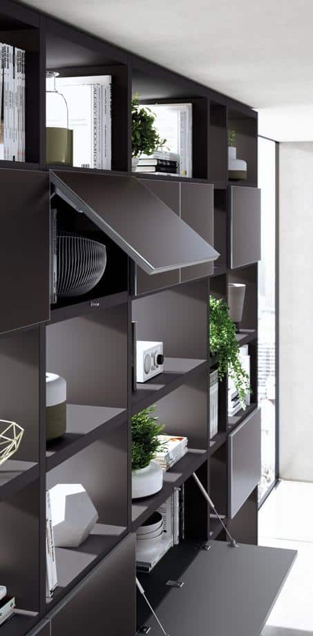 Modern wall-mounted shelving unit with books, decor, and plants, featuring a few open compartments.