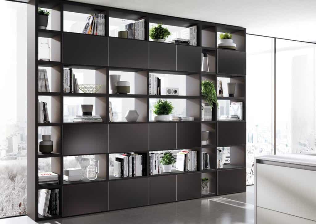Modern bookshelf with plants, books, and decorative items in front of large windows.