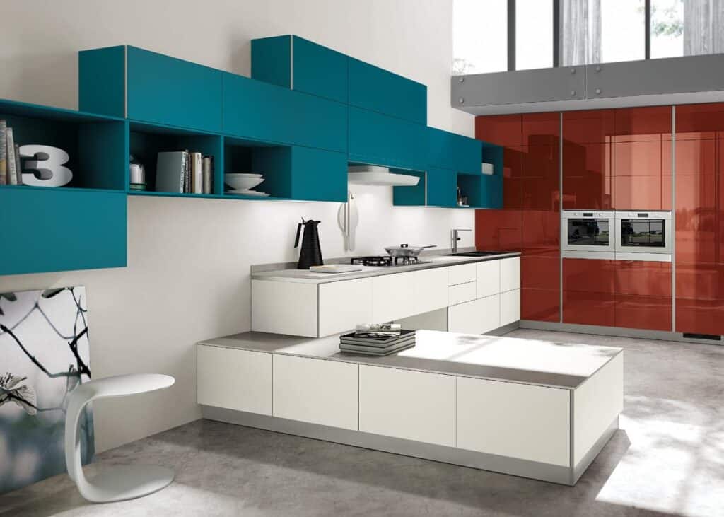 Modern kitchen with teal wall cabinets, white lower cabinets, and red paneling with built-in ovens.