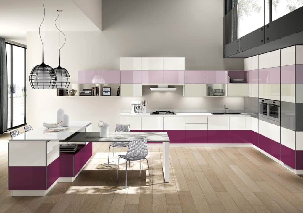 Modern kitchen with white and purple cabinets, wooden flooring, and a dining table with chairs. Two black pendant lights hang above the table.