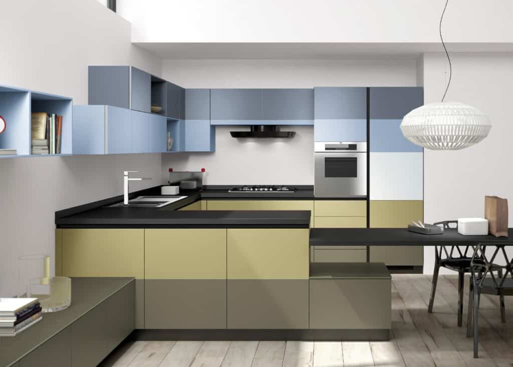 Modern kitchen with blue and olive cabinets, black countertops, built-in appliances, and a white pendant light above a dining table with black chairs.