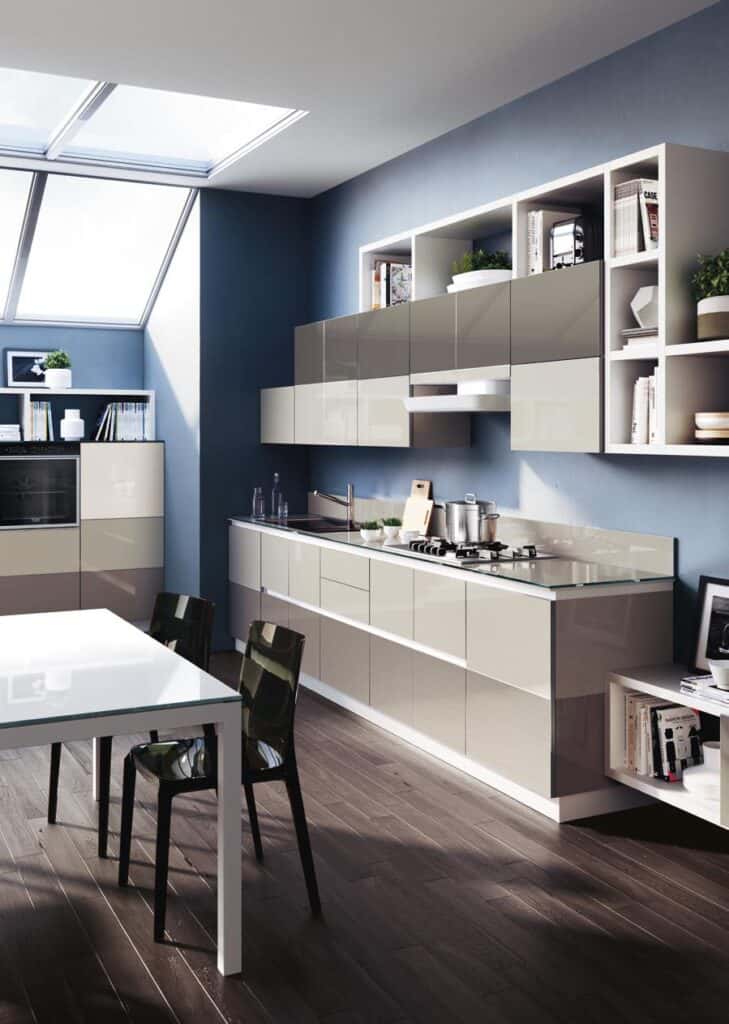 Modern kitchen with sleek cabinets, a gas stove, oven, and a white dining table with black chairs, under large skylights on a wooden floor.