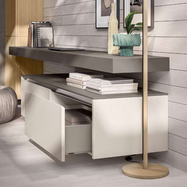 Modern living room with a sleek white cabinet, open drawers, decorative items, a wall-mounted shelf, and framed artwork on a light wood-paneled wall.