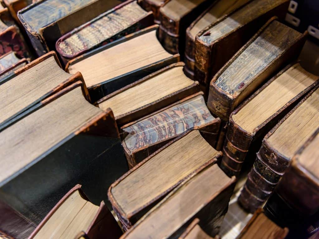 A close-up of stacked vintage books with worn leather covers and agedpages.