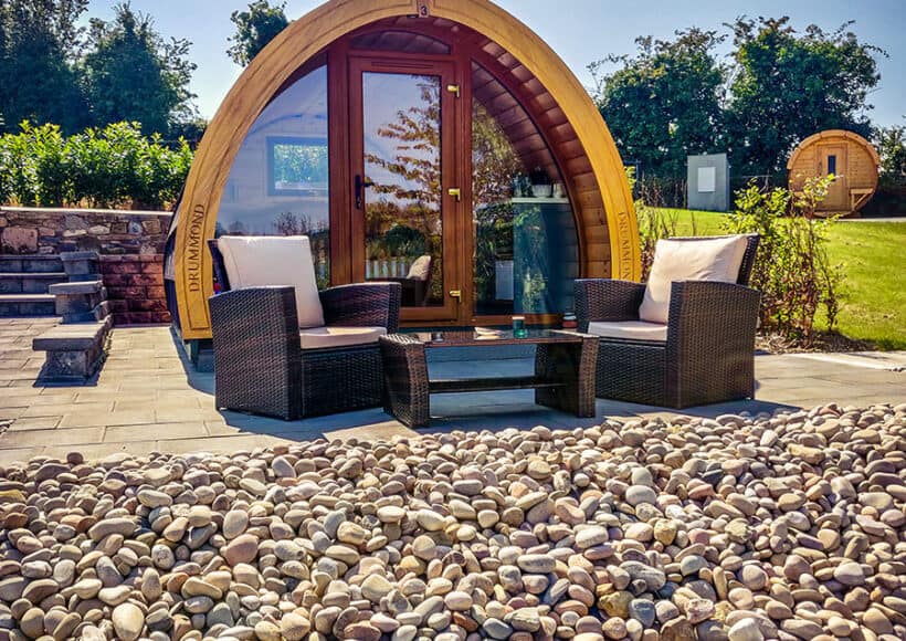 Relaxing outdoor seating with a unique wooden pod in a scenic Irish garden.