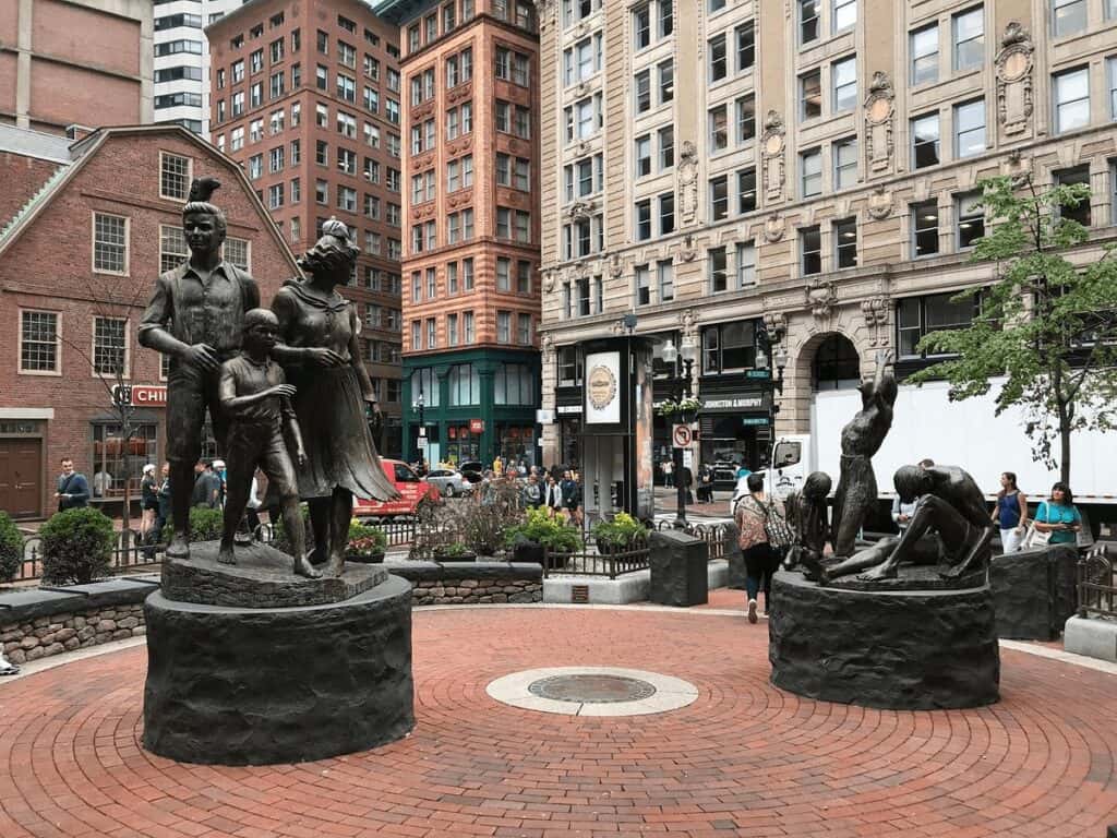 Bronze statues of families and children in an urban city square.