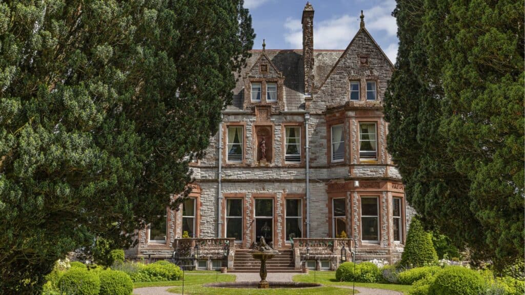 Elegant Victorian mansion surrounded by lush garden greenery in Ireland.