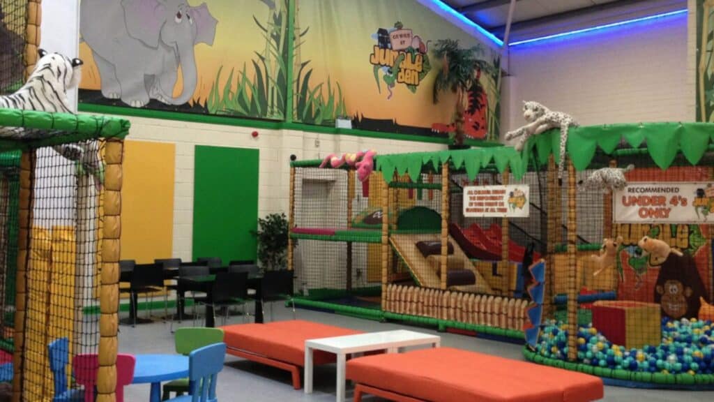 Indoor jungle-themed children's play area with soft play structures and animal decorations.