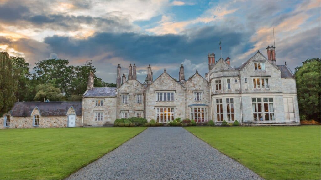 Grand Irish castle with lush green lawns at sunset, showcasing Irish heritage and architecture.