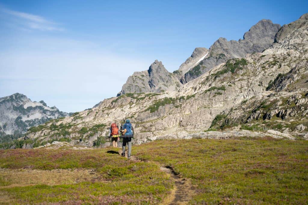 Hikers trekking through Irish mountain landscape with stunning rocky formations and colourful flora.