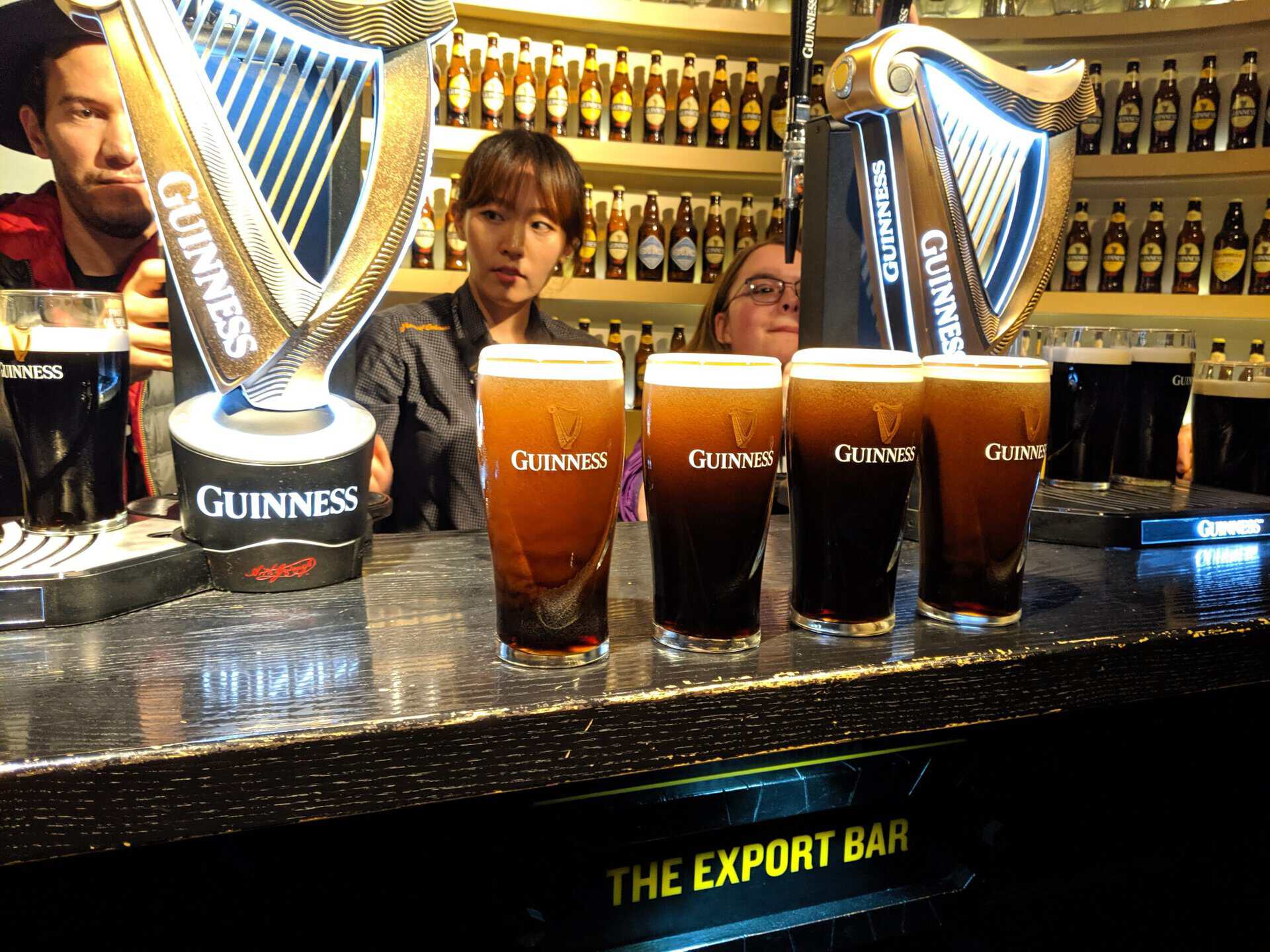 Guinness pints on bar in Dublin with bartenders.