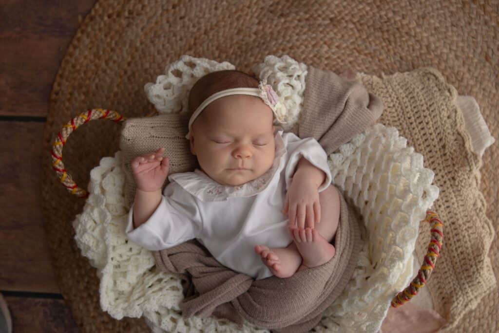A serene image of a newborn baby peacefully sleeping in a cozy wicker basket with soft blankets.