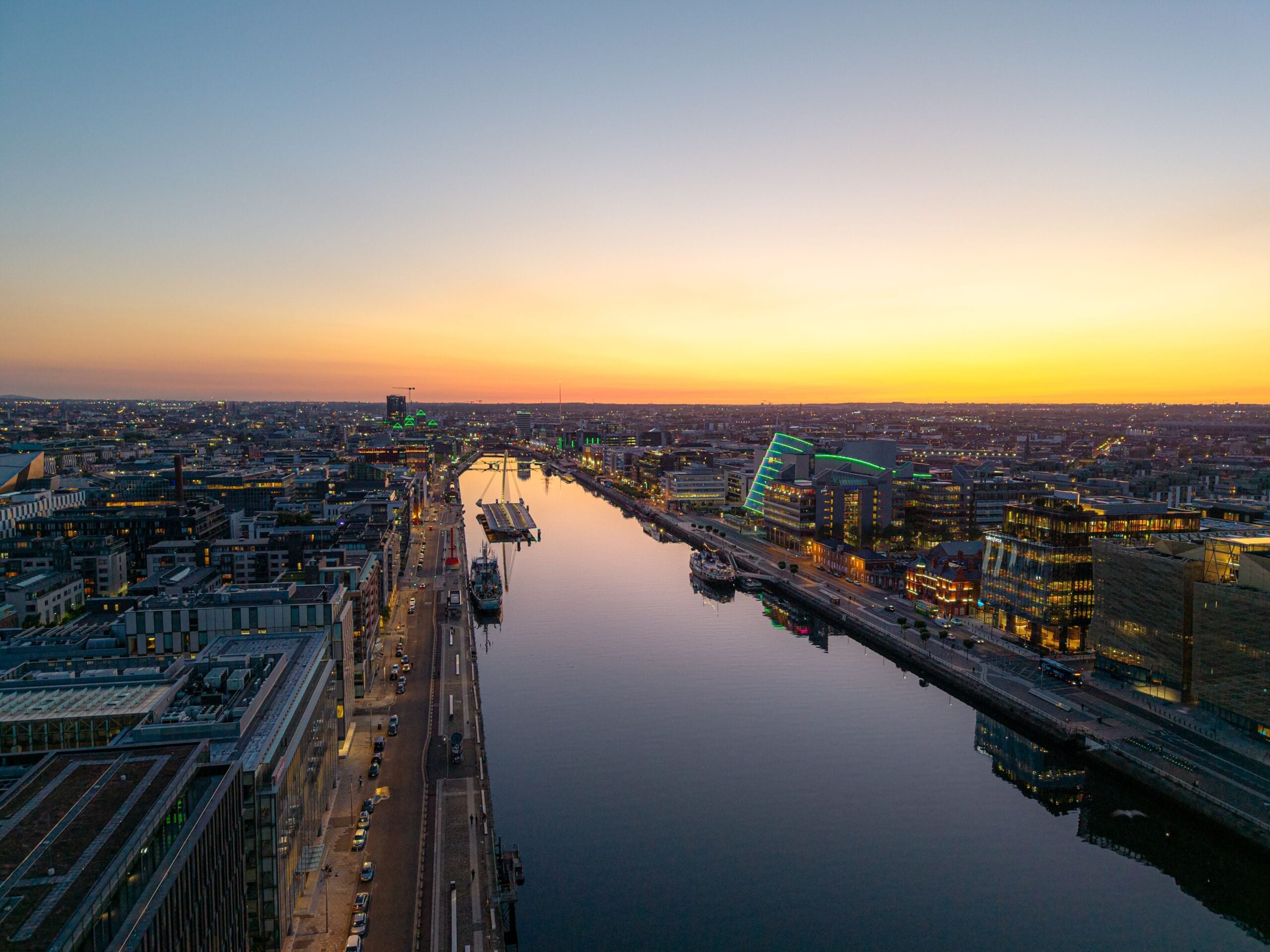 Dublin city skyline with River Liffey at sunset, city lights beginning togl.