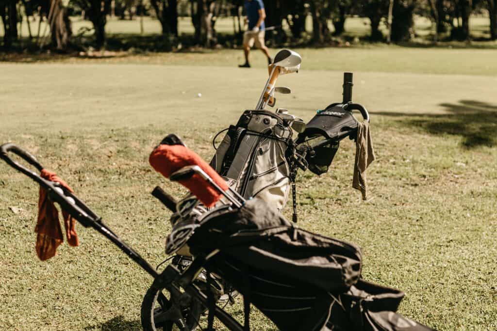 Golf bag with clubs on Irish golf course, green grass, and trees.